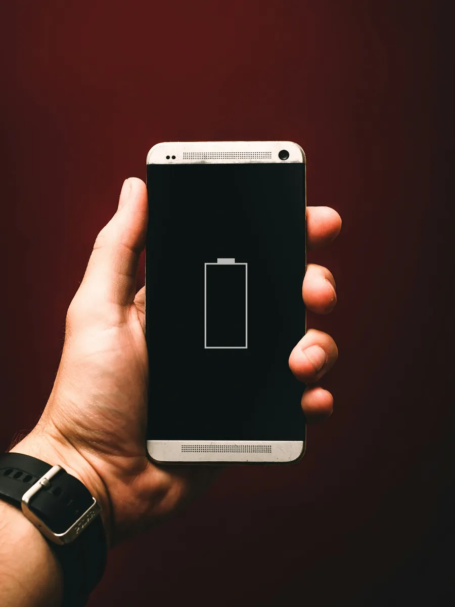 iPhone tenu à la main affichant une batterie presque vide