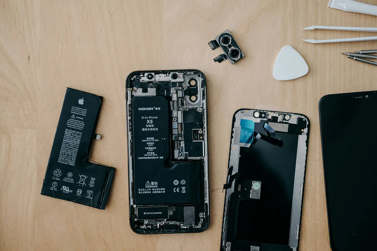 Intérieur d'un iPhone démonté&nbsp;: carte mère, batterie et écran posés sur l'établi