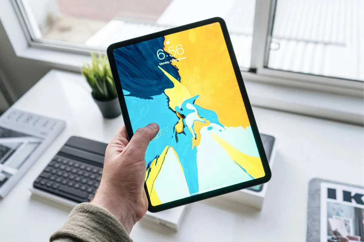 iPad tenu à la main au-dessus d'un bureau